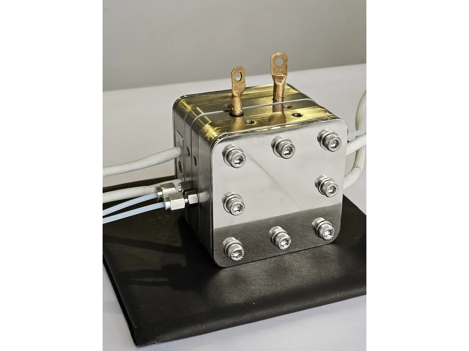 High Temperature PEM/AEM Electrolyzer Hardware - front three-quarter view showing the bolt pattern and both brass current tabs
