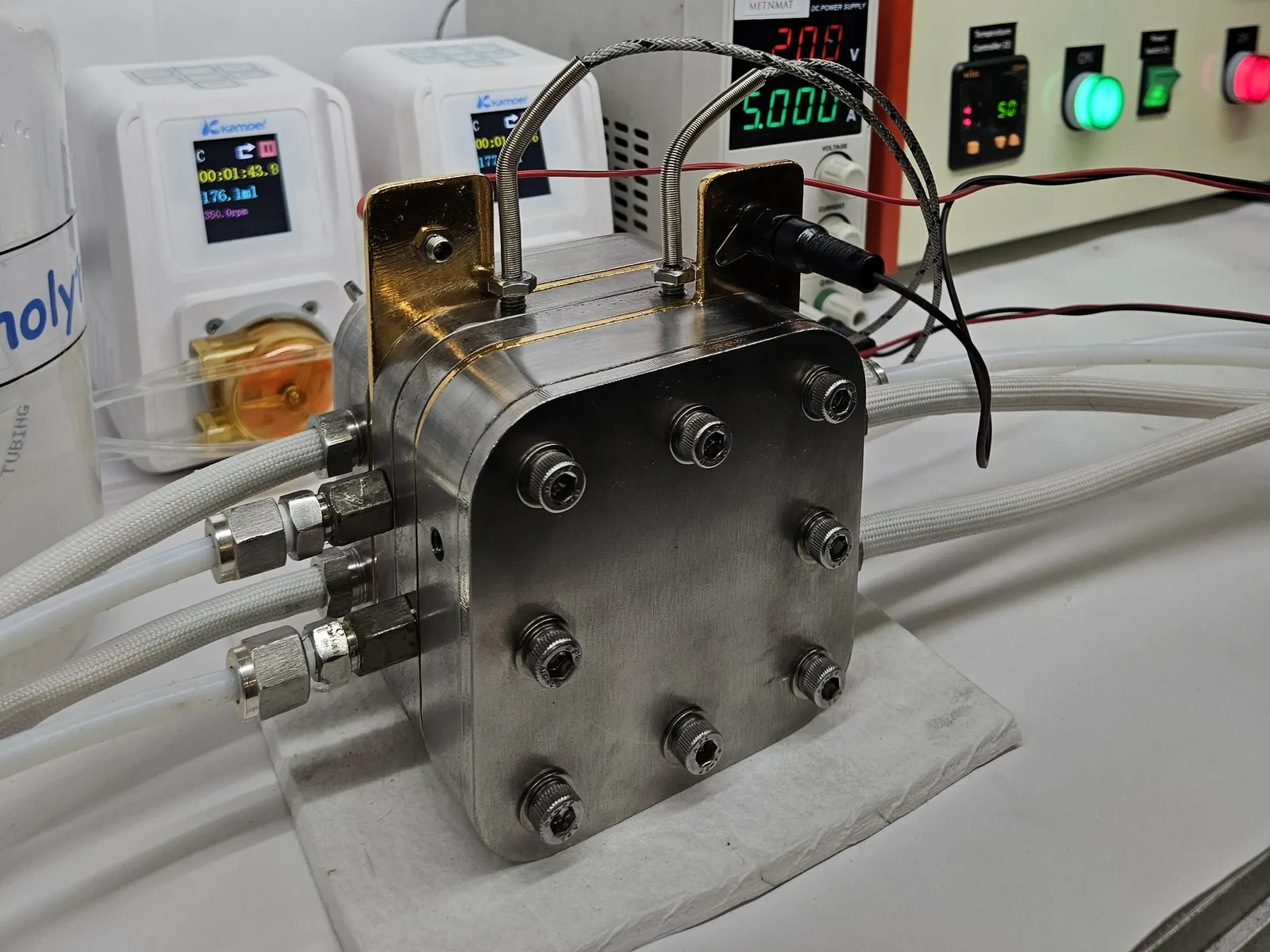 High Temperature PEM/AEM Electrolyzer Hardware - the cell connected to a peristaltic pump and bench power supply during operation